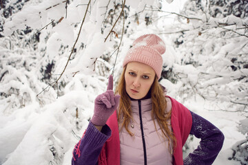 winter emotional woman in pink hat having fun in the forest with snow