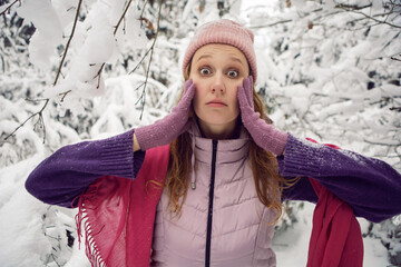 winter emotional woman in pink hat having fun in the forest with snow