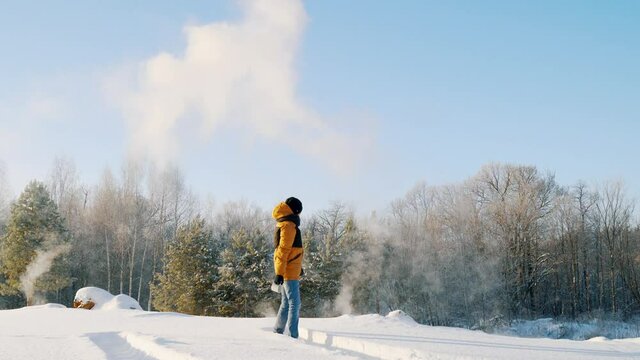 The young man, with a sharp wave of his hand, pours hot water from a cup. The paradoxical "Mpemba effect". Effect of the blast of frosty smoke signal.