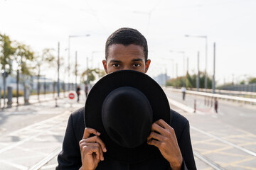 Young man covering face with hat in city