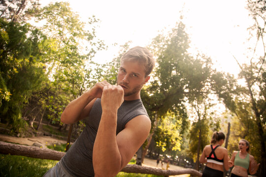Sportsman practicing shadow boxing while standing with friends in background outdoors