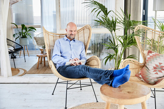 Businessman using computer keyboard while relaxing on chair at home