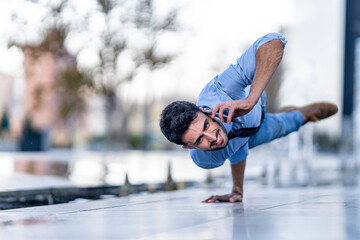 Businessman talking on mobile phone while doing handstand on footpath