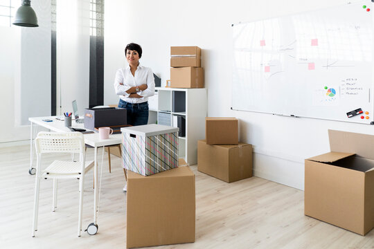 Portrait of businesswoman standing in office filled with cardboard boxes