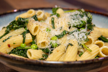 A delicious plate of Pasta with peas and herbs tops off with grated cheese.