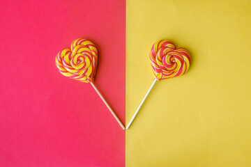 Striped lollipops heart shaped on the yellow-red background. Valentine's day gift.