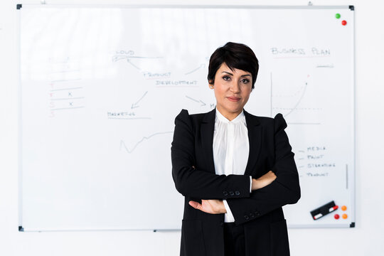 Portrait of businesswoman posing in front of office whiteboard