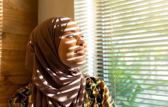 Smiling woman looking through window while standing at cafe