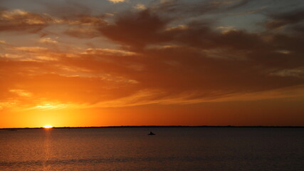 Sun and clouds reflected in on Launa Madre during dazzling sunset while kayak glides by; Texas gulf coast
