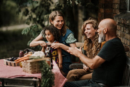 Smiling friends talking while sitting at backyard