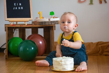 Cute baby boy eating cake while sitting on floor at home