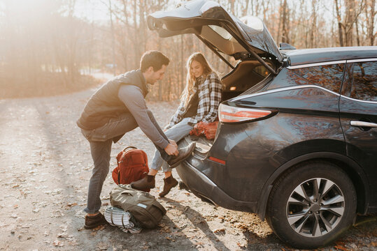 Young couple leaving car before hiking in autumn forest
