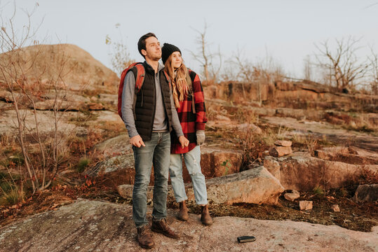 Young couple standing together and admiring surrounding landscape during autumn hike