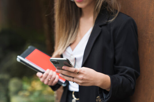 Young female professional text messaging through smart phone