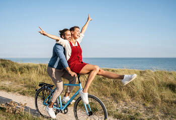 Carefree couple enjoying bicycle ride against clear sky