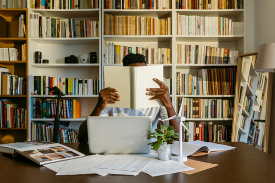 Male environmentalist researching while sitting at desk against bookshelf