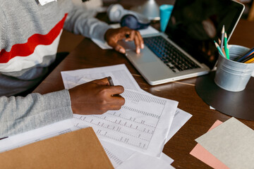 Male financial advisor doing tally on paper by laptop at home