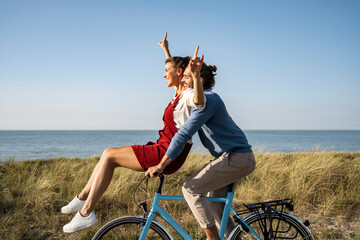 Happy couple enjoying bicycle ride together against clear sky