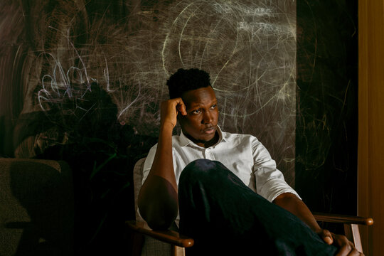 Thoughtful businessman sitting on chair against scribbled wall