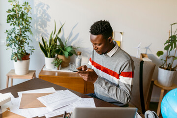 Male financial advisor taking photo of account document on desk at home office