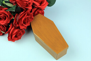 Scale model coffin and a bouquet of red roses. Funeral concept.