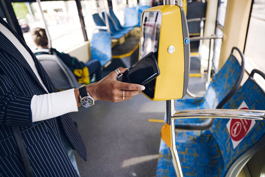 Young woman paying for bus ticket through smart phone