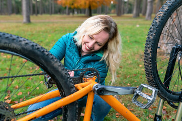 Smiling woman fixing bicycle for riding at Cannock Chase
