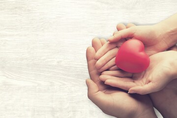 Adult and child hands holding the red heart