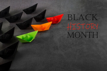 Red, orange, green and black color paper boats. Black history month concept. Flat lay. Copy space.