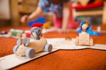 Hands of a child playing with wooden toys at home. Colorful interior of a children's room.