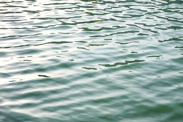 Blurred water surface with waves and green deep lake for background backdrop