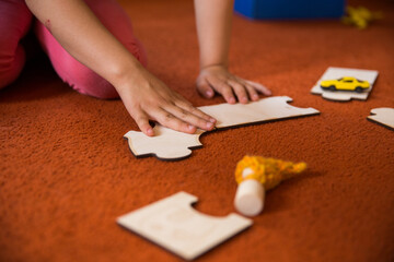 Hands of a child playing with wooden toys at home. Colorful interior of a children's room.