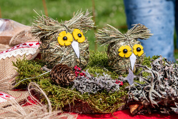 Owl-shaped puppets with yellow eyes handcrafted with straw and natural materials.