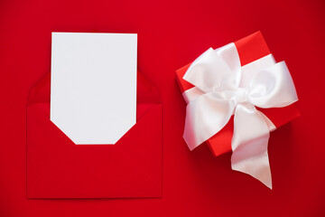 Mockup of greeting card in envelope and present on red background. Happy Valentines or Mothers Day.