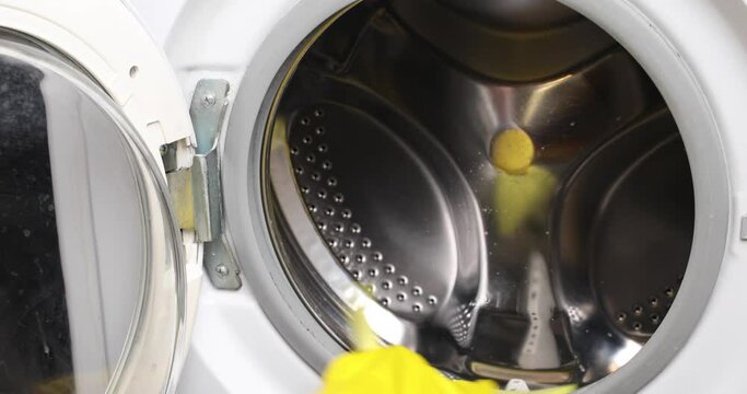 Female hand women in yellow rubber glove washes unsuccessfully dirty gray seal at washing machine.