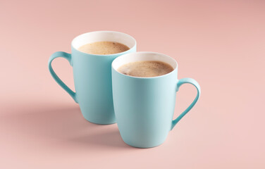 Two light blue mugs with coffee stand on a powdery background, horizontal orientation