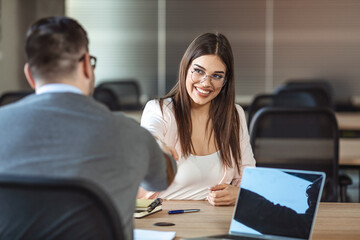 Young woman signing contracts and handshake with a manager. Business people handshake in modern office. Greeting deal concept. Business people talking in modern office.