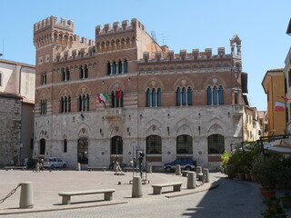Fototapeta na wymiar Aldobrandeschi Palace in Grosseto is a building with a gothic facade built of travertine and bricks and towers decorated by ogival mullioned windows and merlons.