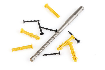 Drill, dowels and screws isolated on white background. Yellow plastic dowel - fasteners and concrete drill. Close-up.