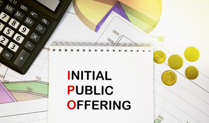 Initial public offering on notepad with calculator, coins, graphics on financial report. Business...