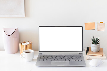 Laptop with blank white screen on home office desk interior. Stylish workplace mockup table view.