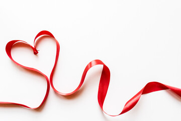 Red ribbon making the shape of a heart on a white background