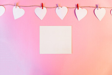 white hearts hanging on a linen thread on a pink  background. A pink background. Composition with hearts and place for writing a message. Background with place for write to valentines day