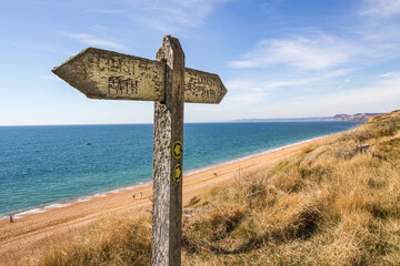 Wooden sign points to the west Dorset coast path near Burton Bradstock