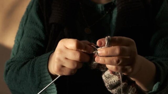 knit a woolen sweater for the winter with knitting needles. close-up of woman's hand doing knitting.