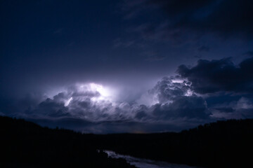 Strong lightning in and behind big towering thunderclouds