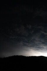 Strong lightning in and behind big towering thunderclouds