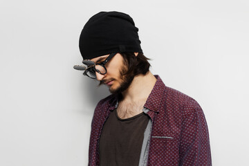 Studio portrait of young hipster guy, wearing round  sunglasses and black hat on white background.