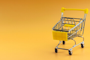 Bsmall shopping cart on yellow background, copy space, shopping concept