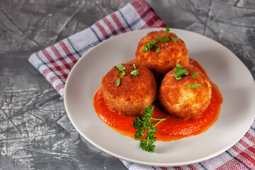 Delicious hot italian arancini - rice balls stuffed with cheese in tomato sauce, in a plate on an old wooden table